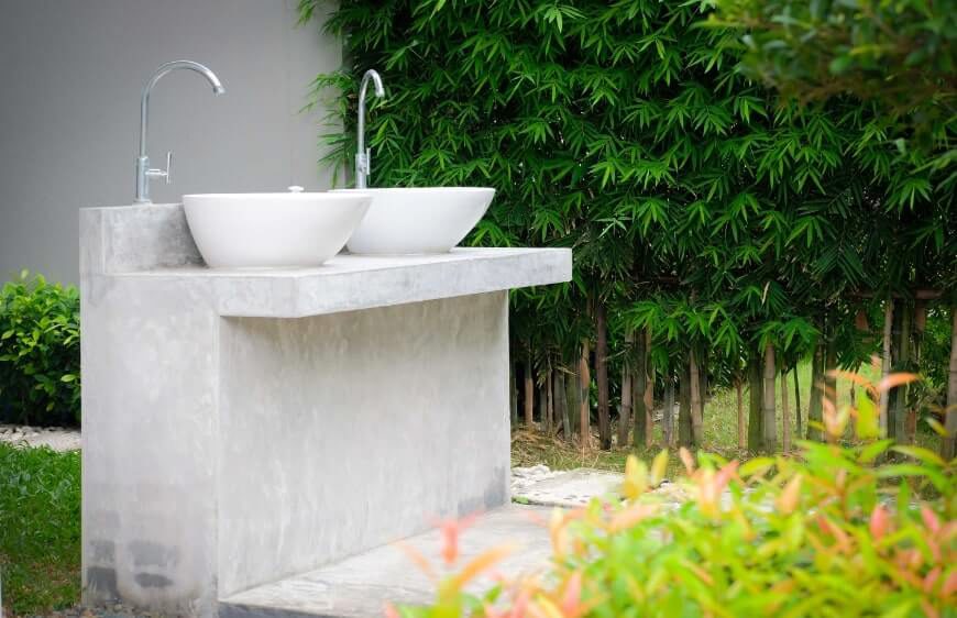 acik yesillik alanda brut beton lavabo alani ve ikiz tezgah ustu canak lavabo