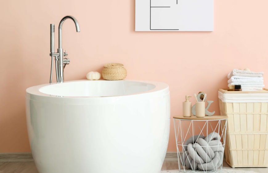 banyo duvarinda somon rengi boya, hasir sepetler, yuvarlak formlu kuvet